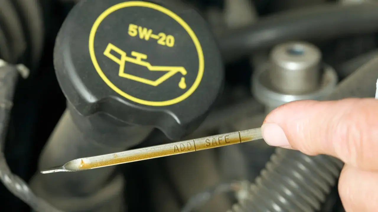 Sprawdzanie poziomu oleju silnikowego. Na bagnecie widoczne oznaczenia "ADD" i "SAFE", a na korku symbol i oznaczenie 5W-20.