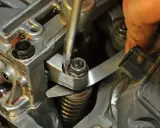 Precyzyjna regulacja zaworów w silniku. Mechanik używa narzędzi do ustawienia luzów.