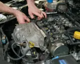 Mechanik sprawdza czujnik położenia wału w silniku samochodowym.