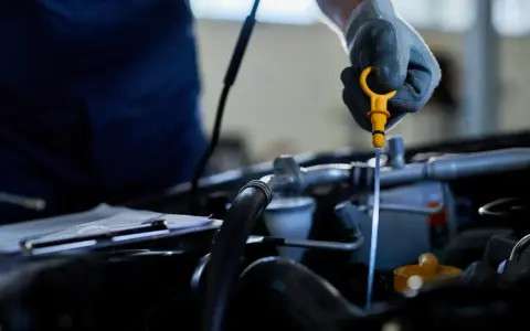 Mechanik w rękawiczce sprawdza poziom oleju za pomocą miarki. To ważny element kontroli, by odma olejowa działała prawidłowo.
