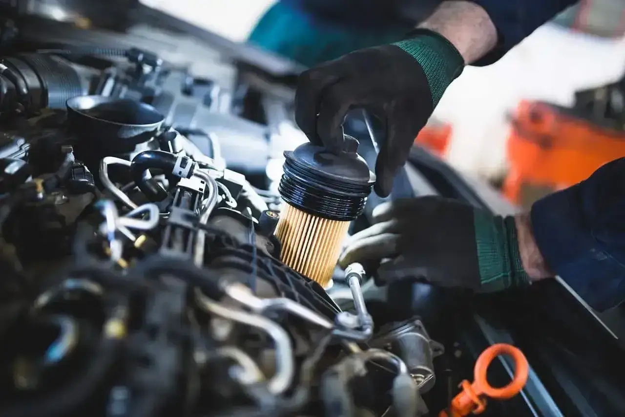 Mechanik wymienia filtr paliwa, co może pomóc w rozwiązaniu objawów zatkanego filtra paliwa, takich jak nierówna praca silnika.