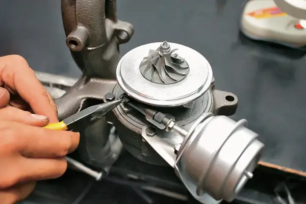 Dłoń z kombinerkami reguluje mechanizm turbosprężarki, precyzyjnie ustawiając geometrię turbiny.